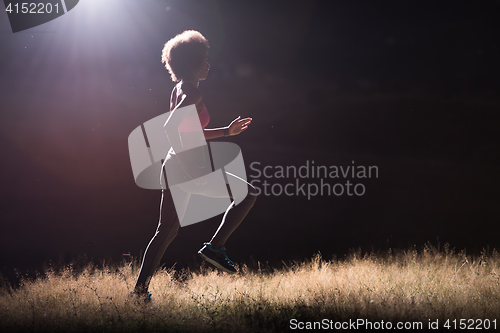 Image of Young African american woman jogging in nature