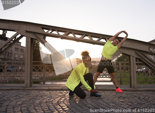 Image of jogging couple warming up and stretching in the city