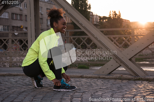 Image of African american woman runner tightening shoe lace