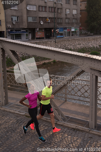 Image of young multiethnic couple jogging in the city