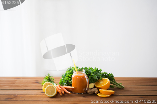Image of glass jug of carrot juice, fruits and vegetables