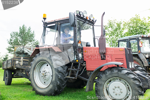 Image of senior man driving tractor at farm