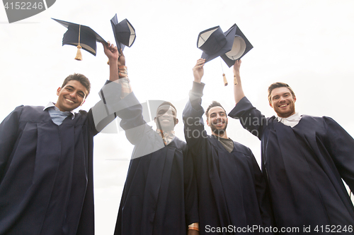 Image of happy students or bachelors waving mortar boards