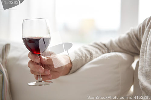 Image of close up of hand holding glass with red wine