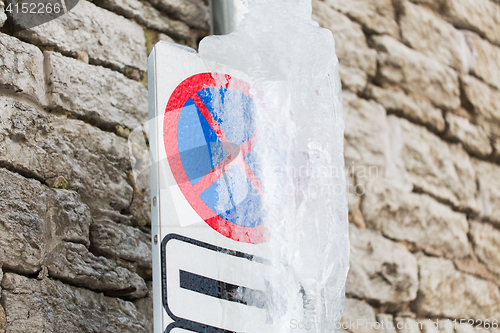 Image of ice-covered no stopping road sign over wall