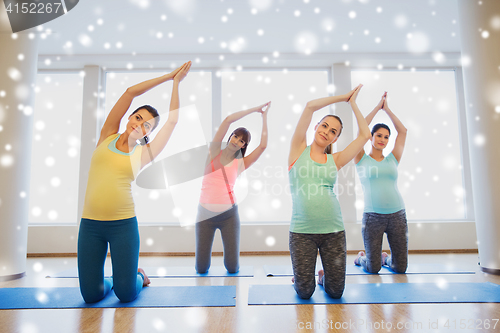 Image of happy pregnant women exercising on mats in gym