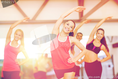 Image of group of smiling people stretching in the gym