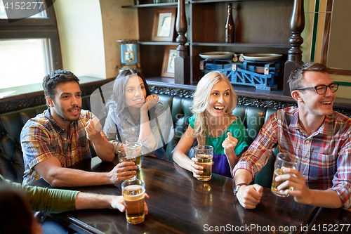 Image of friends with beer watching football at bar or pub