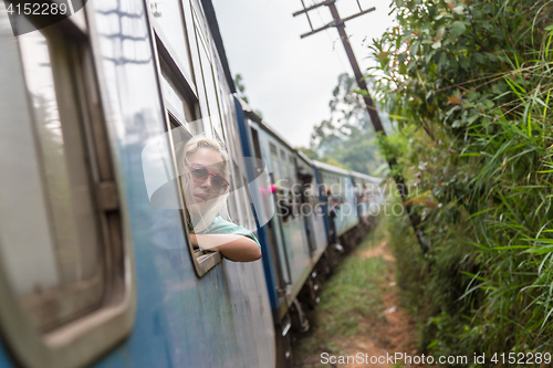 Image of Blonde caucasian woman riding a train, looking trough window.