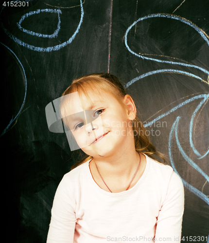 Image of little cute girl in classroom at blackboard writing smiling, preschooler from back alone, lifestyle people concept