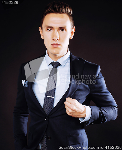 Image of young pretty business man standing on black background, modern h