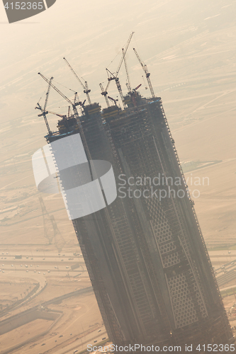 Image of Skyscrappers construction site with cranes on top of buildings.