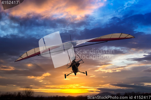 Image of Motorized hang glider flying in the sunset