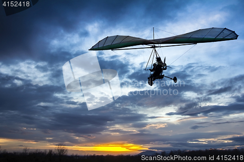 Image of Motorized hang glider flying in the sunset