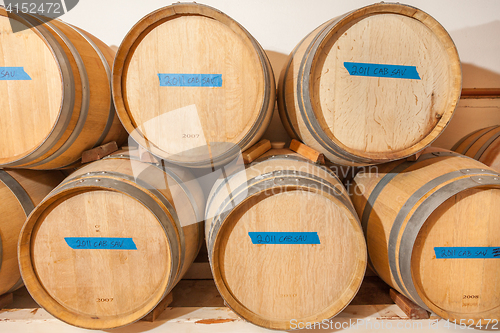 Image of Wine Barrels and Bottles Age Inside Dark Cellar.