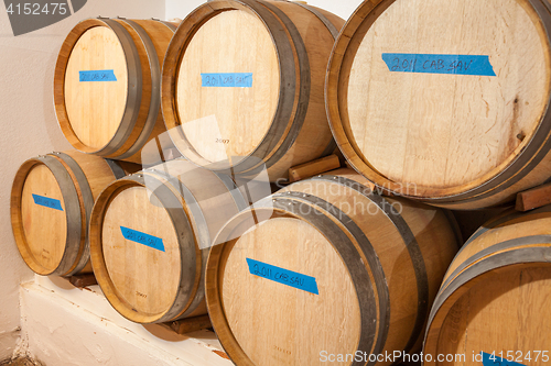 Image of Wine Barrels and Bottles Age Inside Dark Cellar.