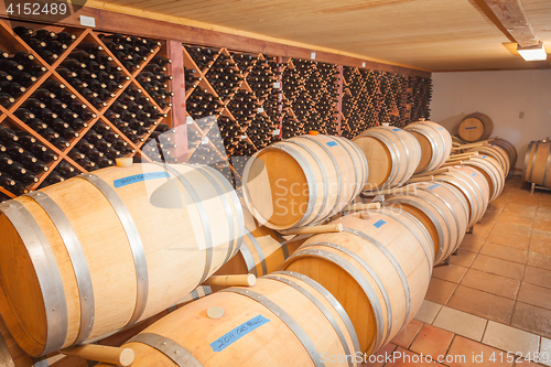 Image of Wine Barrels and Bottles Age Inside Cellar