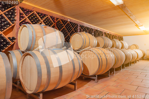 Image of Wine Barrels and Bottles Age Inside Cellar