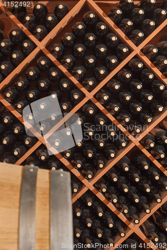 Image of Several Varietal Wine Bottles and Barrel Age Inside Cellar