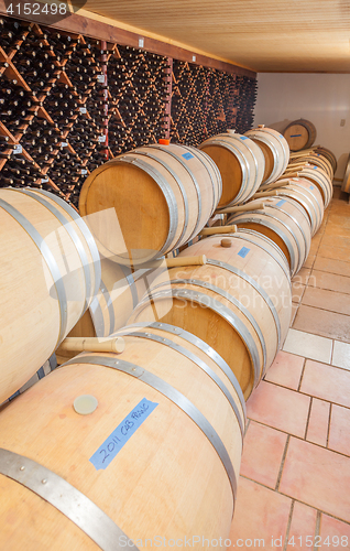 Image of Wine Barrels and Bottles Age Inside Cellar