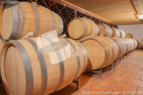 Image of Wine Barrels and Bottles Age Inside Cellar