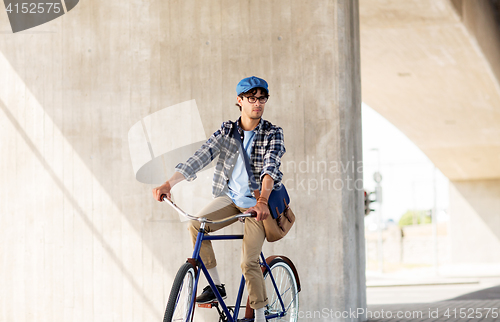 Image of young hipster man with bag riding fixed gear bike