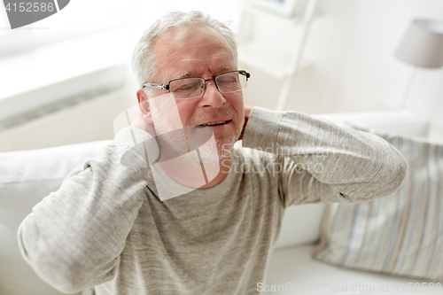 Image of senior man suffering from neckache at home