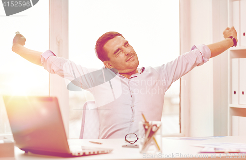 Image of bored businessman with laptop and papers at office