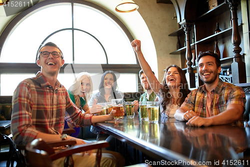 Image of friends with beer watching football at bar or pub