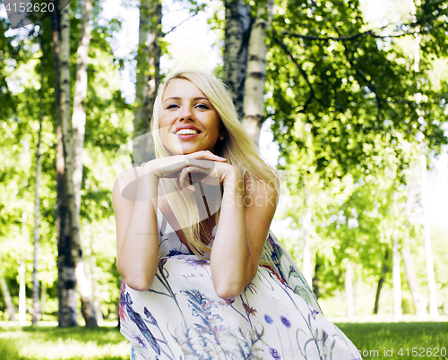 Image of happy blond young woman in park smiling, floral close up