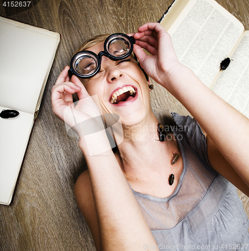 Image of portrait of crazy student girl in glasses with books and cockroaches, concept of modern education people, lifestyle portrait in interior