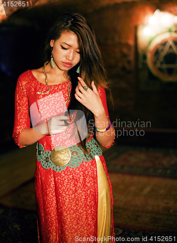 Image of young pretty asian girl in bright colored interior on carpet view