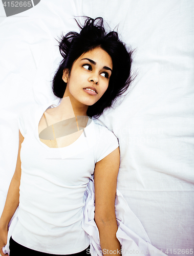 Image of young pretty tan indian mulatto woman in bed among white sheets having fun, trying to sleep, lifestyle people concept