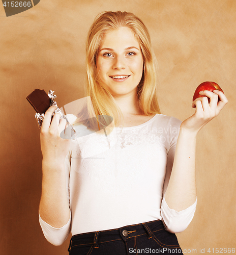 Image of young beauty blond teenage girl eating chocolate smiling, choice