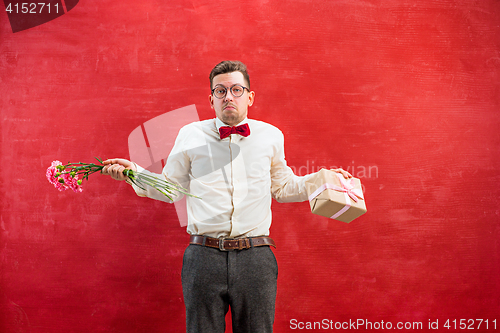 Image of Young young funny man with flowers and gift