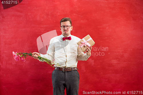 Image of Young young funny man with flowers and gift