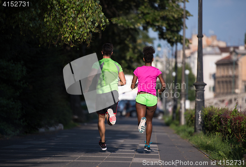 Image of young smiling multiethnic couple jogging in the city