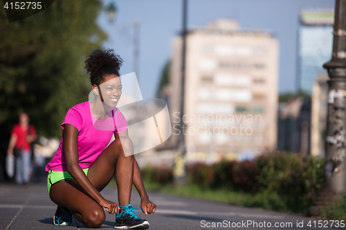 Image of African american woman runner tightening shoe lace