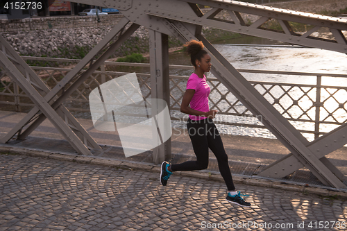 Image of african american woman running across the bridge