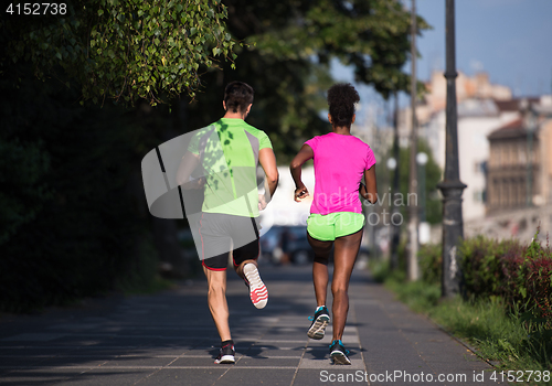 Image of young smiling multiethnic couple jogging in the city