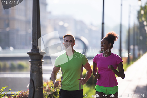 Image of young multiethnic couple jogging in the city
