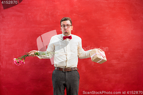 Image of Young young funny man with flowers and gift