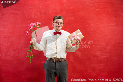 Image of Young young funny man with flowers and gift