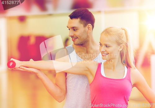 Image of male trainer with woman working out with dumbbell