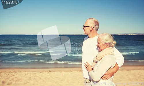 Image of happy senior couple walking along summer beach