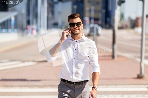 Image of happy man with smartphone calling on city street