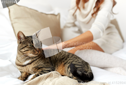 Image of young woman with cat lying in bed at home