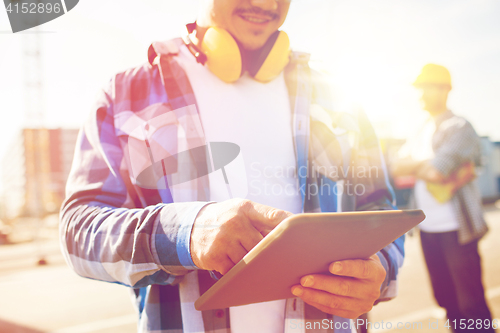 Image of close up of builder with headphones and tablet pc