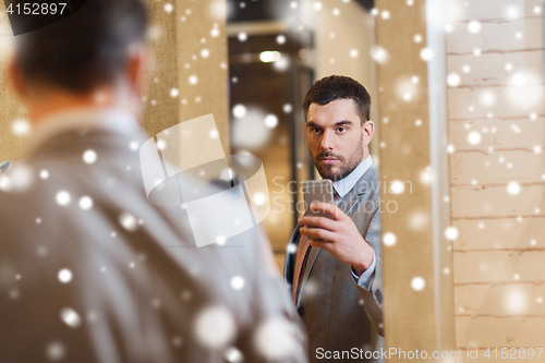 Image of man in suit taking mirror selfie at clothing store