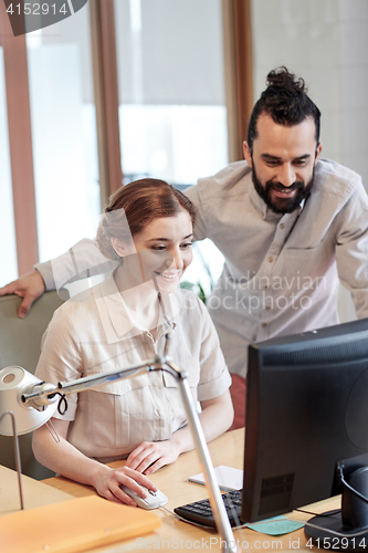 Image of happy creative team with computer in office